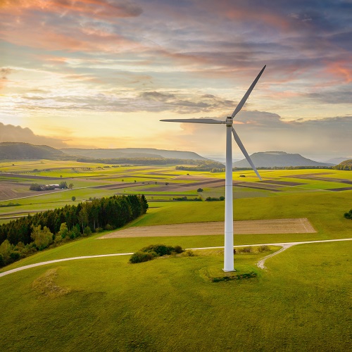 Aerial drone point of view of modern wind turbines in green rural landscape during a colorful sunset twilight. Green Energy, Alternative Energy Environment Concept Shot. Baden Württemberg, South Germany, Europe